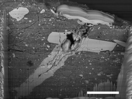 A scanning electron microscope image of a micrometeorite impact crater in a particle of asteroid Bennu material